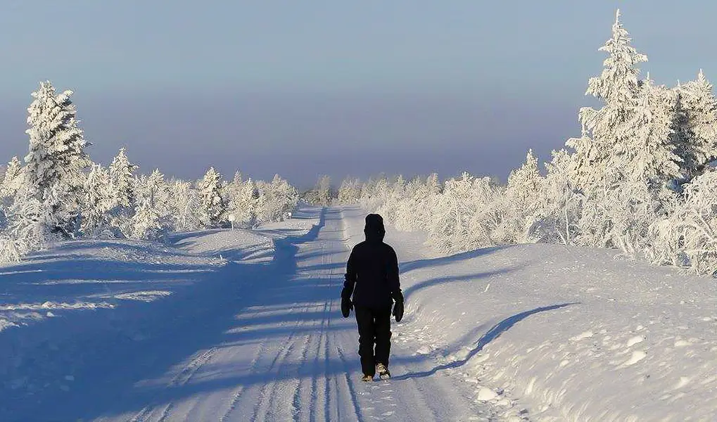 Woman walking on a quiet winter road in Pulju Lapland