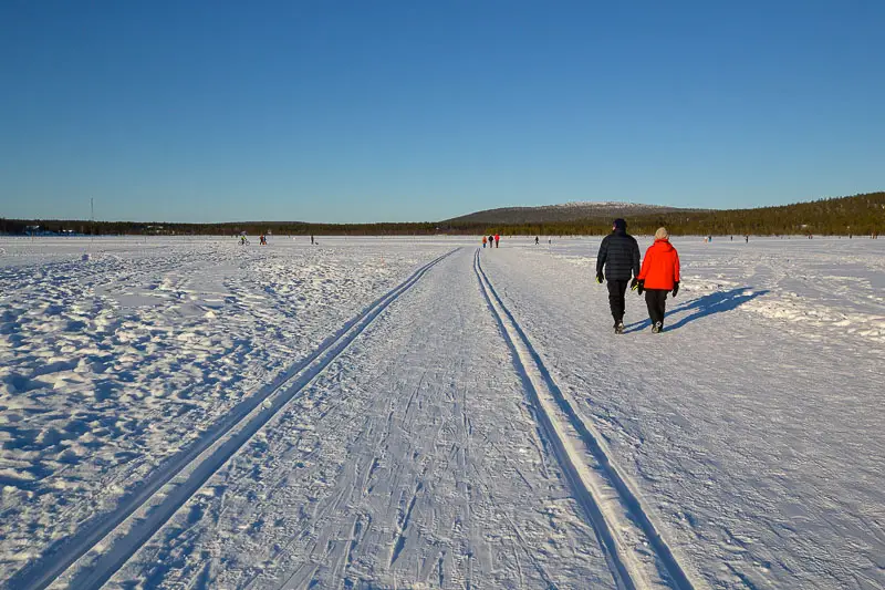 Lomailijat kävelyllä järven jäällä Äkäslompolossa